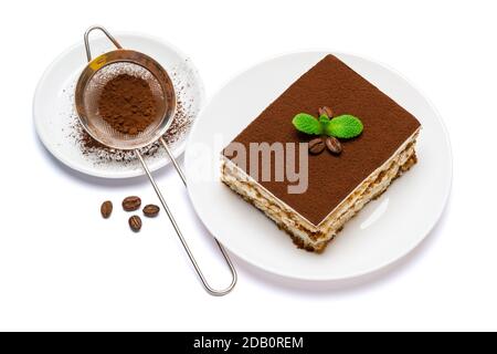 Traditional Italian Tiramisu square dessert portion on ceramic plate and strainer with cocoa powder isolated on white background with clipping path Stock Photo