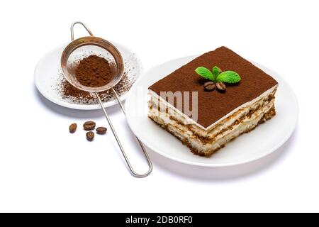 Traditional Italian Tiramisu square dessert portion on ceramic plate and strainer with cocoa powder isolated on white background with clipping path Stock Photo