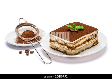Traditional Italian Tiramisu square dessert portion on ceramic plate and strainer with cocoa powder isolated on white Stock Photo