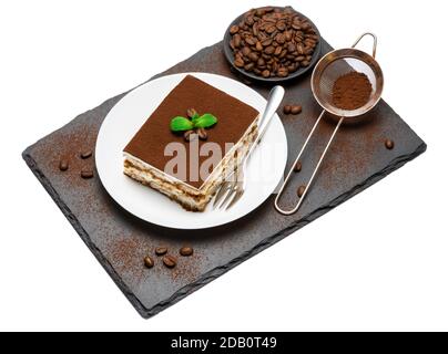 Traditional Italian Tiramisu square dessert portion on ceramic plate, strainer and coffee beans on stone serving cutting board isolated on white Stock Photo