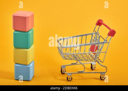 empty wooden cubes mockup style, copy space with shopping trolleys on yellow background. Colourful blocks template for creative design, place for text Stock Photo