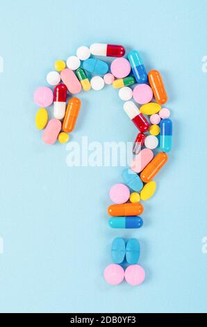A question mark from laid out of medicine pills on blue background. Stock Photo