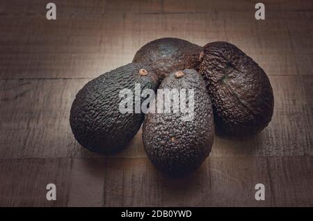 Selective focus on four avocados on a wooden table Stock Photo