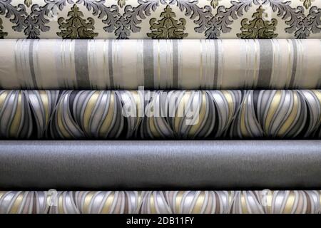 Rolled up rolls of vinyl wallpaper in a building supermarket, shop. Gray, white wallpaper for the wall, decorative finishing materials for the Stock Photo