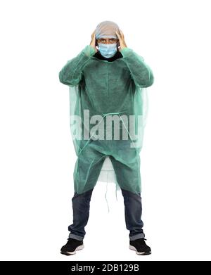 A middle-aged man wearing a surgical gown, a cap and a face mask standing with his hands on his head Stock Photo