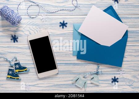 Modern and traditional way to congratulate. Mockup of blank screen smartphone and empty template letter. Christmas or New Year background. Stock Photo