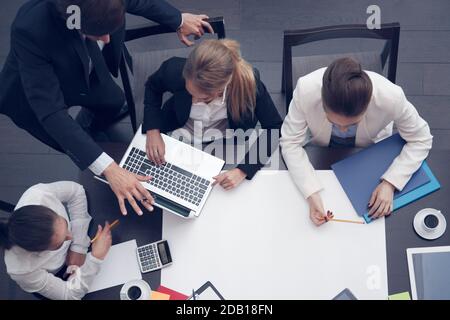 Business people at workplace, cup of coffee, digital tablet, smartphone, papers and various office objects on table, blanl white paper with copy space Stock Photo