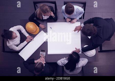Top view of people around table in construction business meeting blank blueprint paper with copy space for text Stock Photo