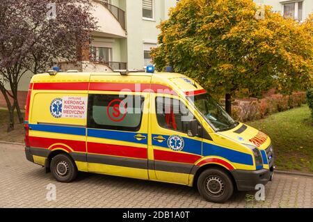 POZNAN, POLAND - Nov 14, 2020: Yellow ambulance van standing in front of a apartment building entrance during the corona virus epidemy in the Stare Ze Stock Photo
