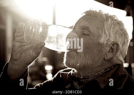 Senior man draining the last drop of beer from a pint glass, England UK Stock Photo