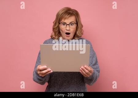 Mature caucasian man holding laptop looking with amazement and shock, using computer. Stock Photo
