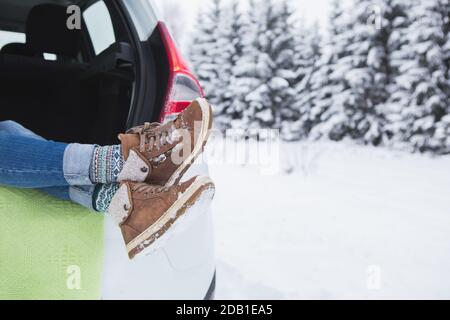 Woman sits in the trunk of the car. Close-up of winter boots Stock Photo