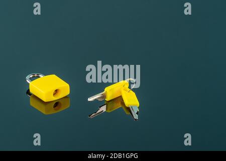 Small yellow Padlock and keys for Backpacks, Luggage, Computer Bags, Locker, Gym on black mirror background Stock Photo