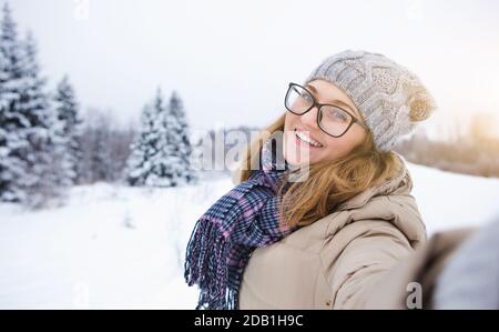 Young woman takes selfie on a background of snow-covered winter forest Stock Photo