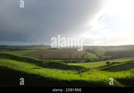The Dorset countryside with the earthworks of Maiden Castle in the foreground - John Gollop Stock Photo