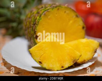 Pineapple fruits on a white plate and red apples in the background Stock Photo