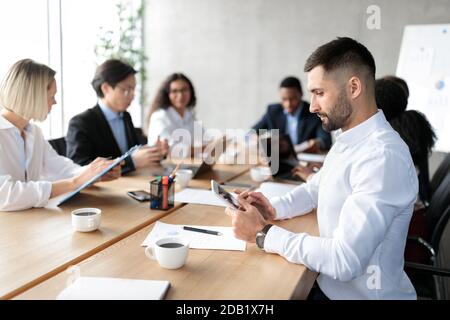 Businessman Using Tablet Computer At Corporate Meeting In Modern Office Stock Photo