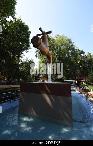 Giant Magic Tap, an outdoor floating tap fountain hovering above a pool, with endless supply of water gushing out of it, seemingly from nowhere, this Stock Photo