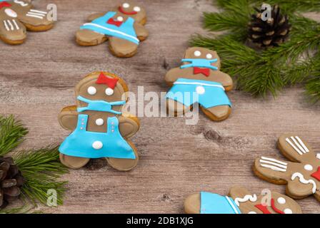 gingerbread man in a medical mask. cookies made with your own hands on a wooden surface. treats for new year's holidays and Christmas Stock Photo