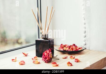 Aroma reed diffuser. Bottle container with wood stick diffusers Essential  oils to scent your home fragnance concept autumn holidays at cozy home on  the windowsill Hygge aesthetic atmosphere on knitted white sweater.