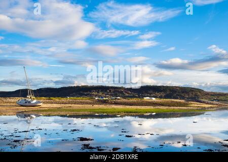 Tranquil scene with clouds reflected in calm sea water at high tide on Welsh coast in Red Wharf Bay, Isle of Anglesey, Wales, UK, Britain Stock Photo