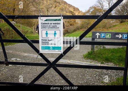 Coronavirus pandemic Covid-19 bilingual sign warning Keep apart maintain social distance in English and Cadwch ar wahan in Welsh on a footpath. Wales Stock Photo