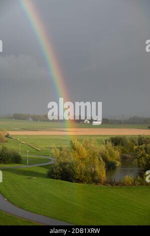 A rainbow visible very close over the green fields in southern Sweden after a summer rain Stock Photo