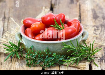 mini roma tomatoes and herbs on wooden background Stock Photo - Alamy