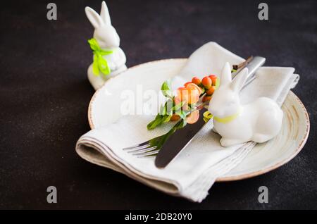 Easter table setting with spring flowering branches, cutlery and decorative rabbits. Spring Easter background for menu. Holidays background with copy Stock Photo