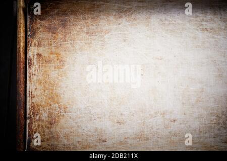 Metal baking tray surface with scratches and old brown stain in cropped overhead background concept