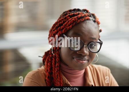 Close up of young African-American woman wearing glasses and looking at camera while posing against blurred background, copy space Stock Photo