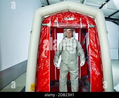 Man wearing a decontamination suit standing in a decontamination tent Stock Photo