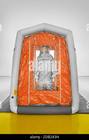 Man wearing a decontamination suit standing in decontamination tent. Stock Photo