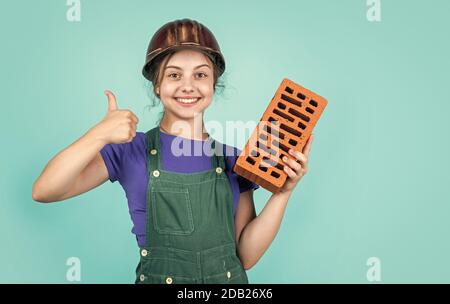 best quality. happy childhood. kid wear protective helmet. protect head on construction site. teen girl hold brick. little builder with brick. child is engineer architect. building her future house. Stock Photo