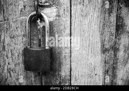 Padlock is hanging on a grungy wooden gate, close up photo Stock Photo