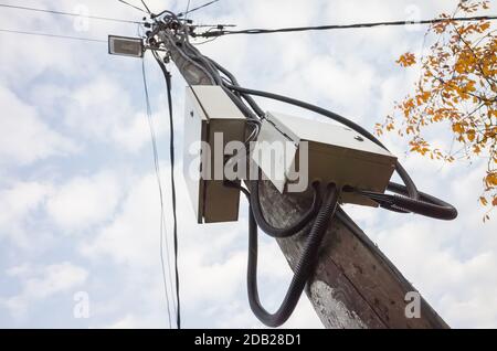 Power pole with street light, electrical distribution boxes and wires is under cloudy sky at day Stock Photo