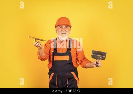 Work for real men. Plastering tools for plaster. plaster trowel spatula on yellow drywall plasterboard. Plasterer in working uniform plastering. man with spatula. process of applying layer of putty. Stock Photo