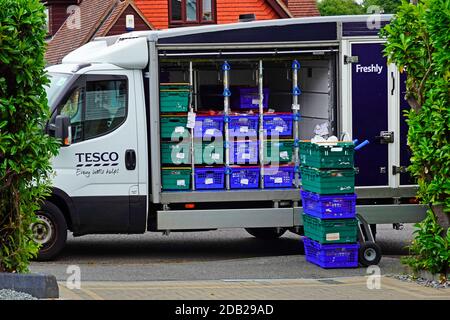 Close up of parked  open side Tesco supermarket grocery van food online shopping home delivery to house with boxes of groceries on trolley England UK Stock Photo