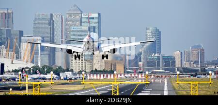 British Airways airplane landing London City Airport Newham with O2 arena & Canary Wharf in London Docklands skyline beyond Tower Hamlets England UK Stock Photo