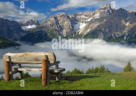 Wooden bench above the Fischlein Valley in the Sexten Dolomites invites you to rest. Above the bank in the distance the Drei Zinnen can be seen, on the top right the Dreischusterspitze taly Stock Photo