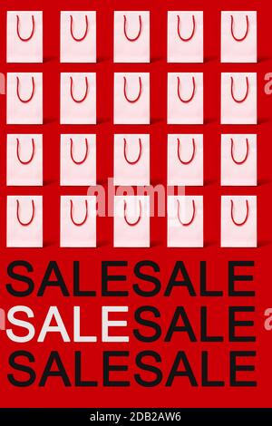 some white paper shopping bags with red handles and the word sale on a red background Stock Photo