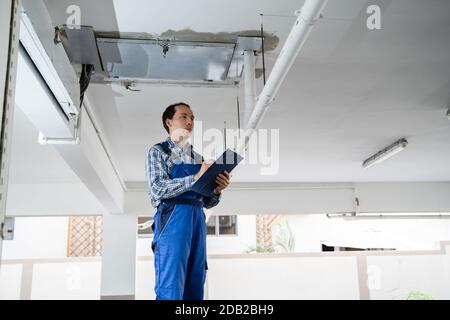 Male Worker Inspecting Pipes In Residential Building Stock Photo