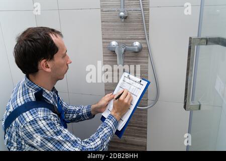 Young Male Plumber Checking Faucet In Shower Stock Photo