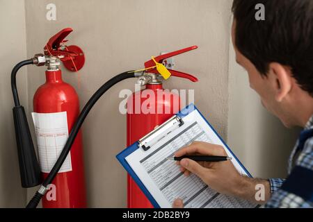 Male Professional Checking The Condition Of A Fire Extinguisher Stock Photo