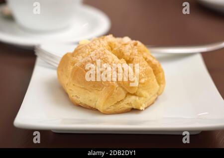 round baked eclair cake with cream on a white plate, selective focus Stock Photo