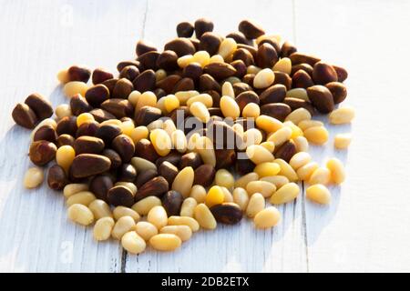 Peeled kernels of cedar nuts in a spoon, two pine cones, green branches Stock Photo