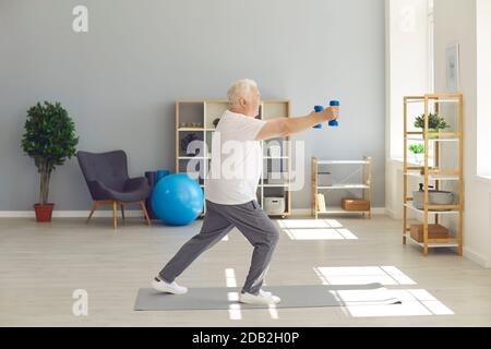 Active, sporty, healthy senior man doing fitness exercise with dumbbells at home Stock Photo