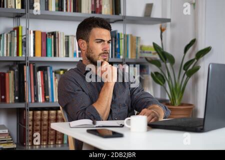 Handsome male businessman working on laptop from home Stock Photo