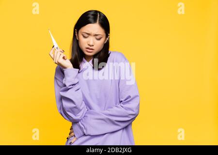 sick asian woman holding digital thermometer isolated on yellow Stock Photo