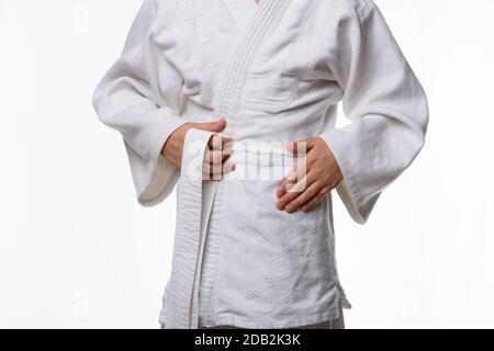 Stages of correct tying of the belt by a teenager on a sports kimono, step two Stock Photo